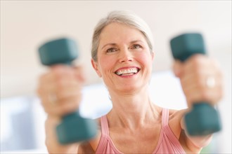 Portrait of senior woman exercising with dumbbells in gym.
