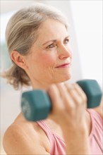 Portrait of senior woman exercising with dumbbells in gym.