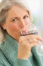 Senior female connoisseur tasting red wine.