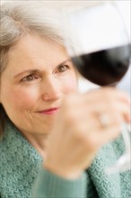 Senior female connoisseur tasting red wine.