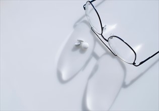Close up of glasses and pills on white background, studio shot.