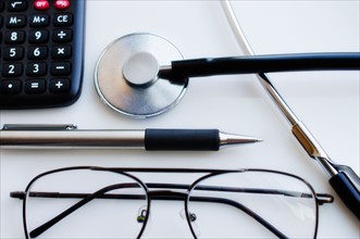 Close up of pen, glasses and calculator and stethoscope, studio shot.