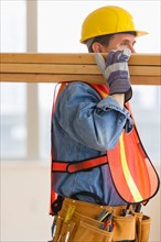 Construction worker carrying planks.
