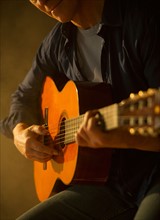 Close up of man playing acoustic guitar, studio shot.