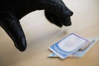 Close up of thief's hand in black glove stealing driver's license, studio shot.