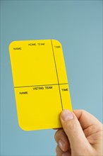 Close up of man's hand showing yellow card, studio shot.