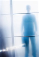 Silhouettes of businessman behind glass door.