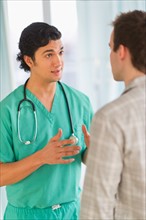 Male doctor talking to male patient in hospital.