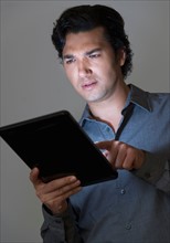 Studio shot of businessman using digital tablet.