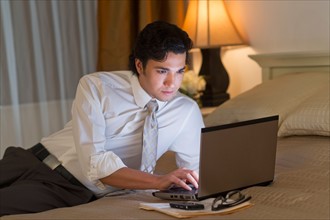 Businessman working on laptop in hotel room.