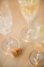Champagne flutes and cork on table. Photo : Jamie Grill
