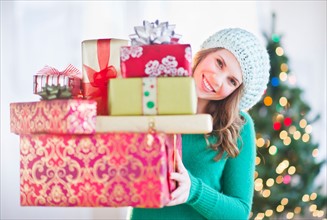 Young woman with stack of colorful Christmas gifts. Photo : Daniel Grill