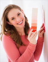 Portrait of smiling young woman holding color samples. Photo : Daniel Grill