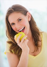 Portrait of smiling young woman holding apple. Photo : Daniel Grill
