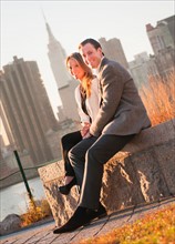 USA, New York, Long Island City, Portrait of smiling young couple, Manhattan skyline in background.