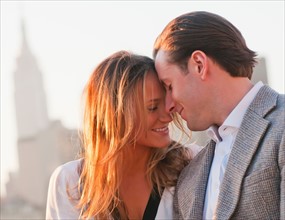 USA, New York, Long Island City, Close-up of happy young couple, Manhattan skyline in background.