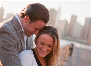 USA, New York, Long Island City, Young couple flirting on bridge, Manhattan skyline in background.