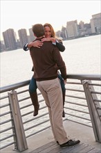 USA, New York, Long Island City, Young couple embracing on boardwalk. Photo : Daniel Grill