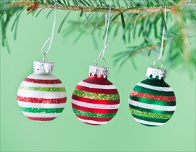 Studio shot of striped Christmas ornaments hanging on Christmas tree. Photo : Daniel Grill