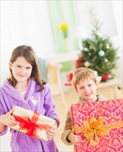 Girl (8-9) and boy (6-7) holding christmas gifts. Photo : Daniel Grill