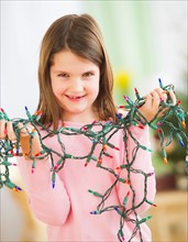 Portrait of girl (8-9) with christmas lights. Photo : Daniel Grill