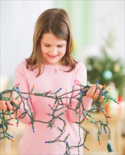 Portrait of girl (8-9) with christmas lights. Photo : Daniel Grill