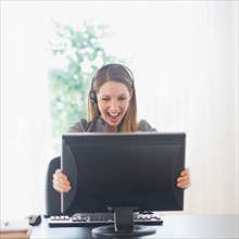 Happy young woman holding computer monitor. Photo : Daniel Grill