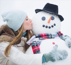Young woman kissing snowman. Photo : Daniel Grill
