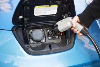 Close-up of man charging electric car. Photo : fotog