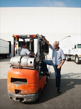 Two men working with forklift.