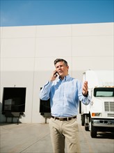Businessman talking on phone outside warehouse.