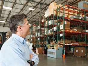 Businessman looking at goods in warehouse.