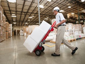 Man pushing hand truck in warehouse.