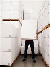 Worker carrying boxes in warehouse.