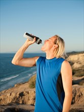 USA, California, San Diego, Male jogger drinking water from bottle.