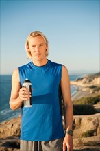 USA, California, San Diego, Portrait of male jogger holding water bottle.