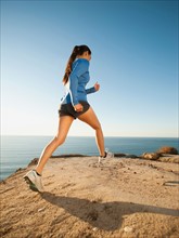 USA, California, San Diego, Woman jogging along sea coast.