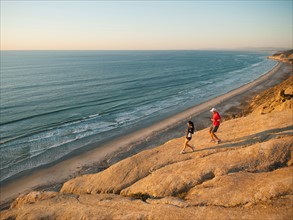 USA, California, San Diego, Man and woman jogging along sea coast.