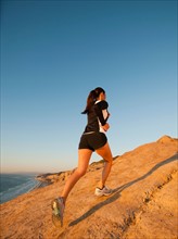 USA, California, San Diego, Woman jogging along sea coast.