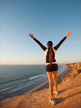 USA, California, San Diego, Woman stretching at beach.
