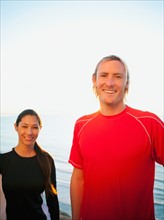Portrait of male and female joggers at sea.