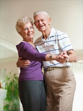 Senior couple dancing at home.