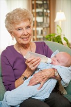 Portrait of senior woman giving milk to grandson (2-5 months).