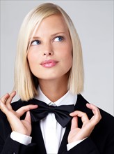 Studio portrait of young waitress adjusting bow tie. Photo : Yuri Arcurs