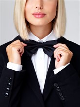 Studio shot of young waitress adjusting bow tie. Photo : Yuri Arcurs