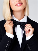 Studio shot of young waitress adjusting bow tie. Photo : Yuri Arcurs