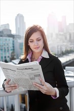 USA, Seattle, Young businesswoman reading newspaper. Photo : Take A Pix Media