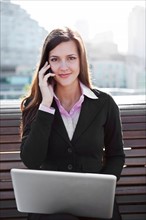 USA, Seattle, Young businesswoman sitting on bench and working. Photo : Take A Pix Media