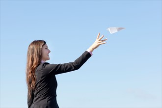Smiling businesswoman throwing paper plane. Photo : Take A Pix Media