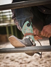 Close-up of cowboy tying shoe. Photo : Mike Kemp